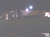 A Peterbilt tractor hauls a flat bed trailer with two Elgin street sweepers